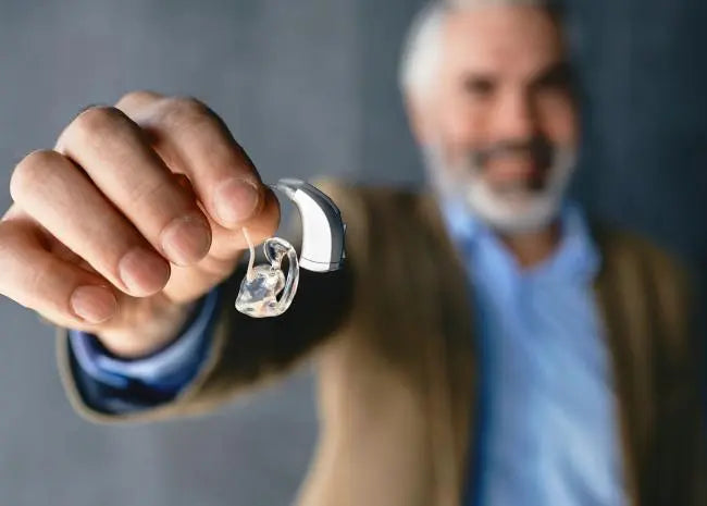 Un homme retire ses aides auditives inconfortables