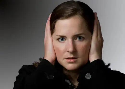Une jeune femme génie par certains bruits se bouches les oreilles avec les mains