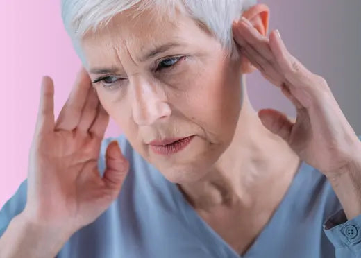 Une dame se tient les oreilles à cause de ses acouphènes