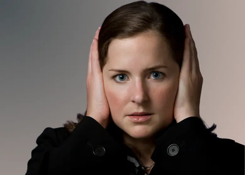 Une jeune femme se bouche les oreilles car elle est trop sensible au bruit
