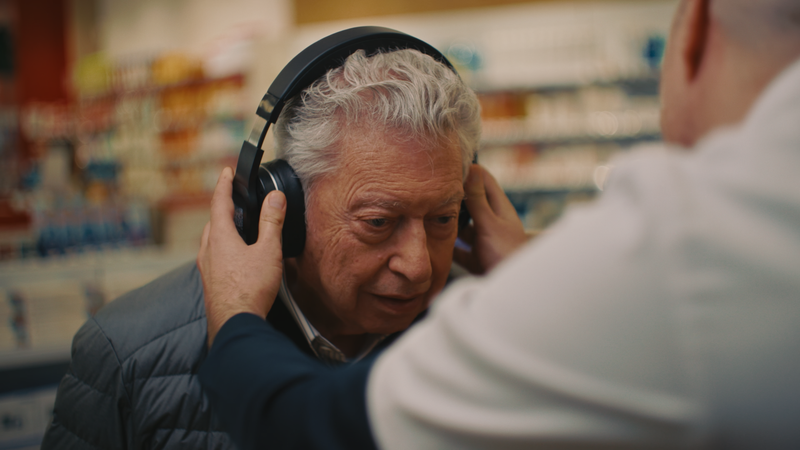 Un pharmacien place le casque Spokeo sur les oreilles d'un patient 
