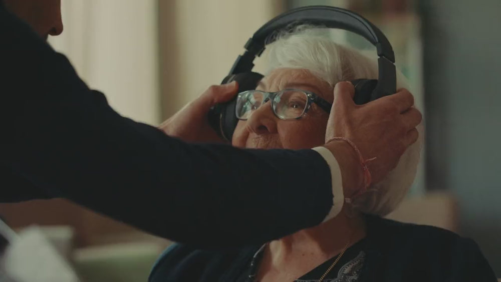 Un aidant pose le casque Spokeo sur les oreilles d'une dame âgée